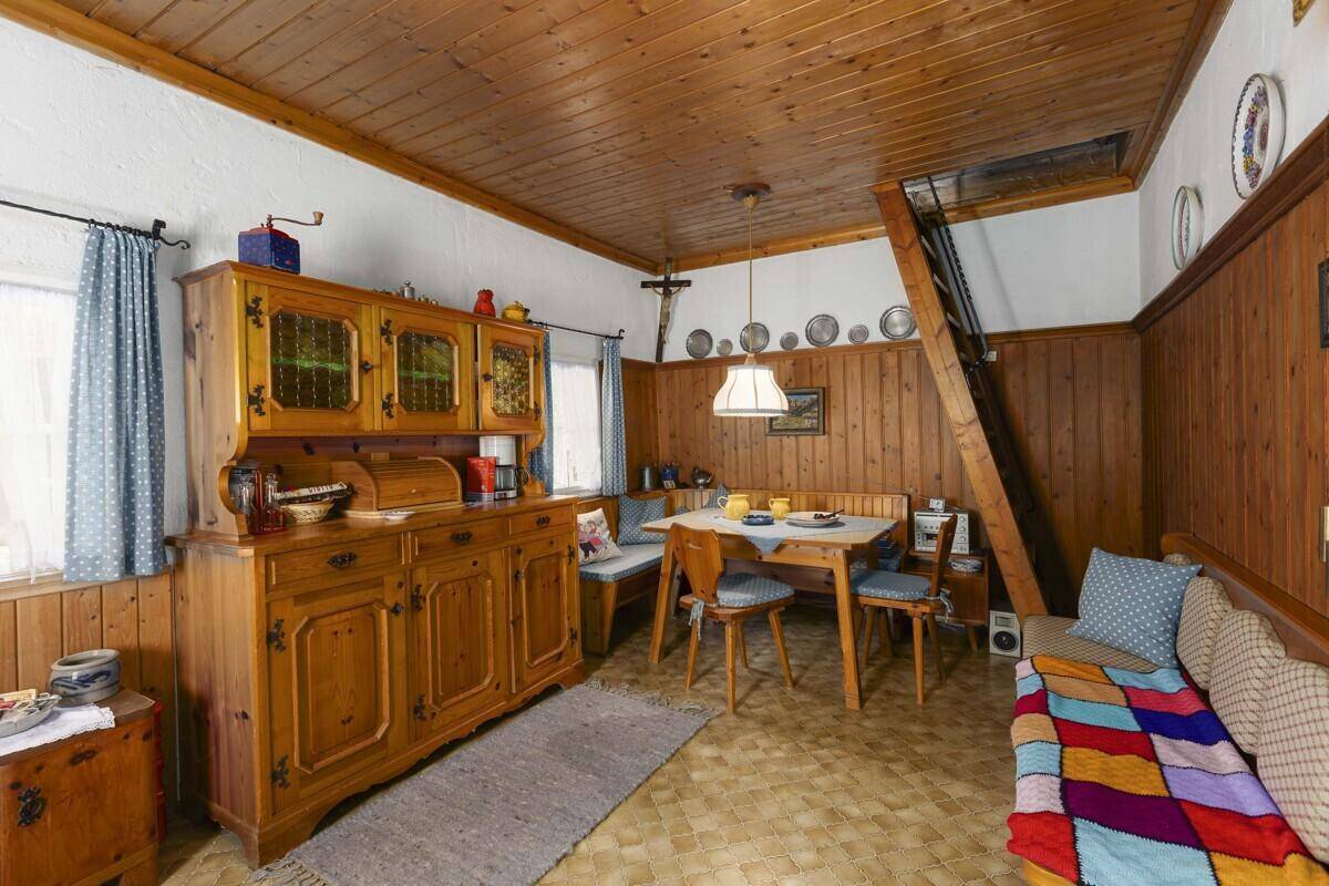 Gemütlicher Wohn-Essbereich im alpinen Stil mit Holztäfelung und traditionellen Möbeln.