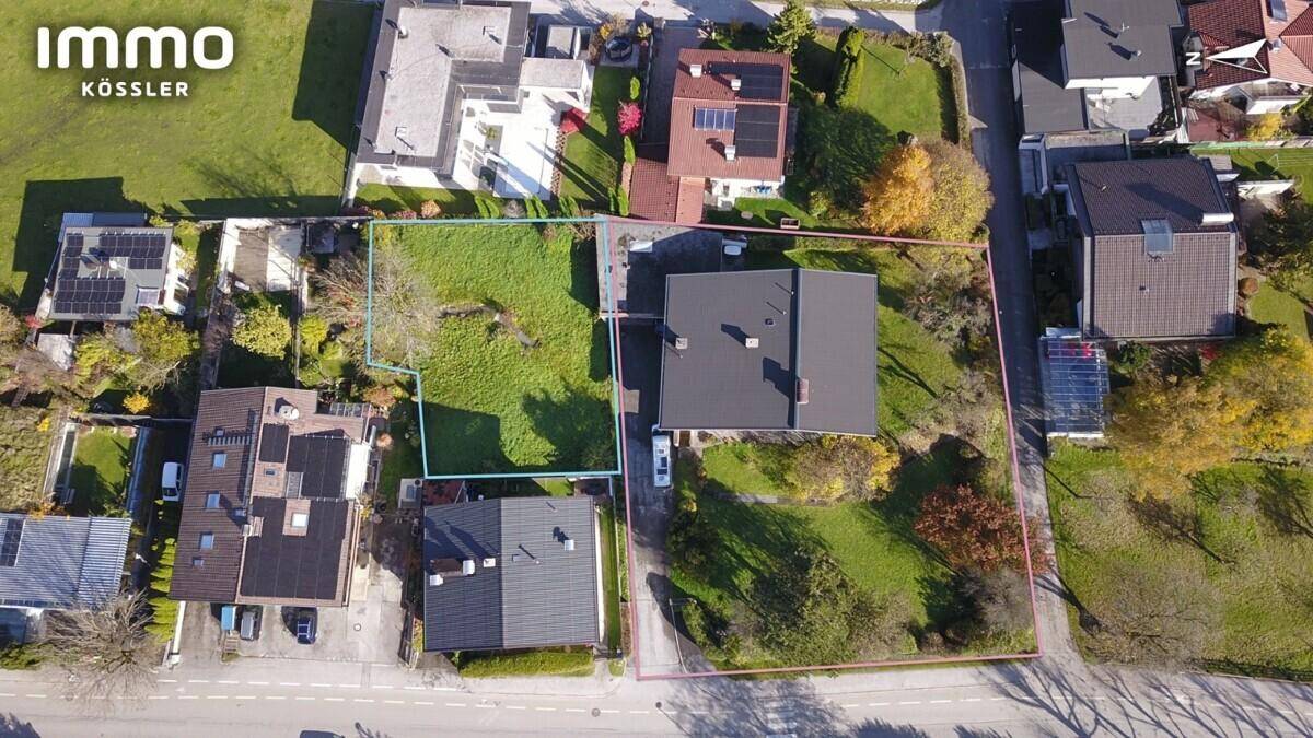 Vogelperspektive eines Wohngebiets mit mehreren Grundstücken, Häusern und grünen Gärten.