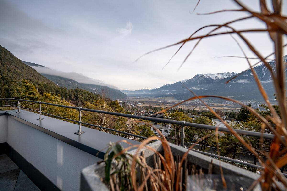 Terrasse mit weitem Blick auf die Berge und das Tal, umgeben von Natur.