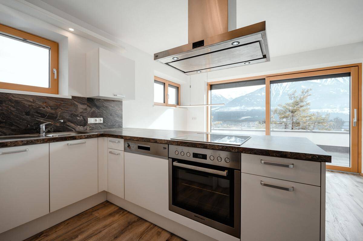 Helle Küche mit modernen Geräten, Bergblick und Zugang zu einem Außenbereich.