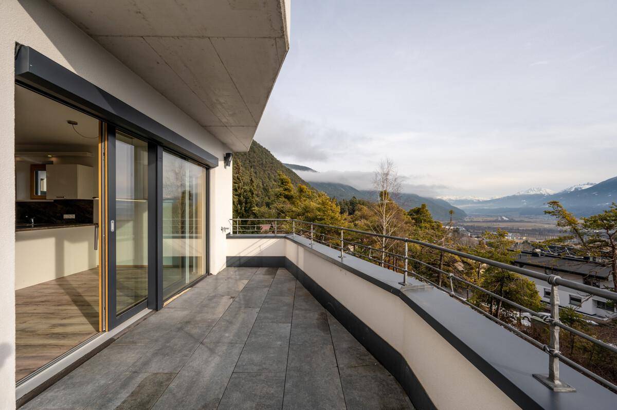 Geräumige Terrasse mit Fliesenboden und weitem Blick auf die umliegende Berglandschaft.