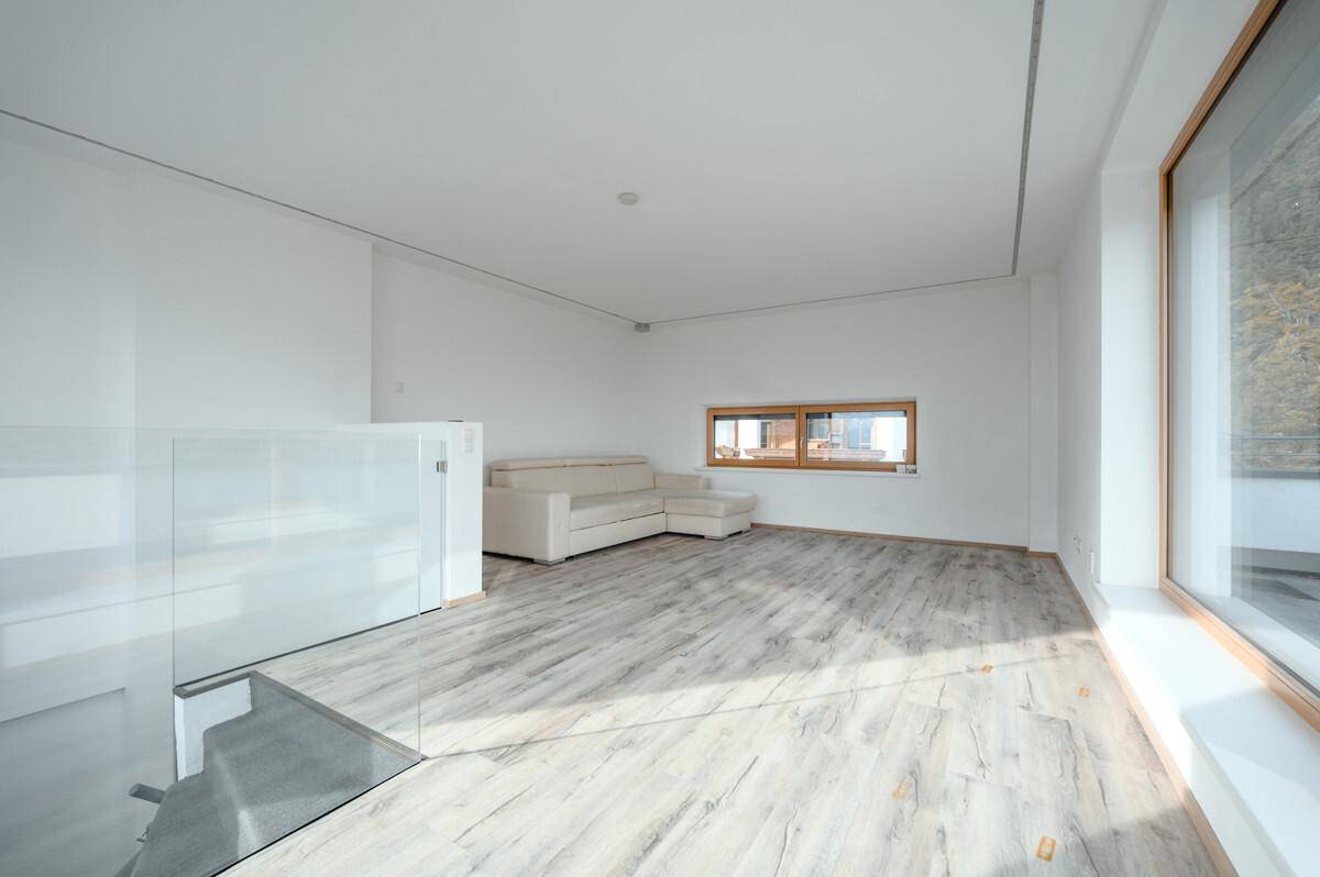 Heller Wohnbereich mit Laminatboden, Sofa und Blick auf die umliegende Landschaft.