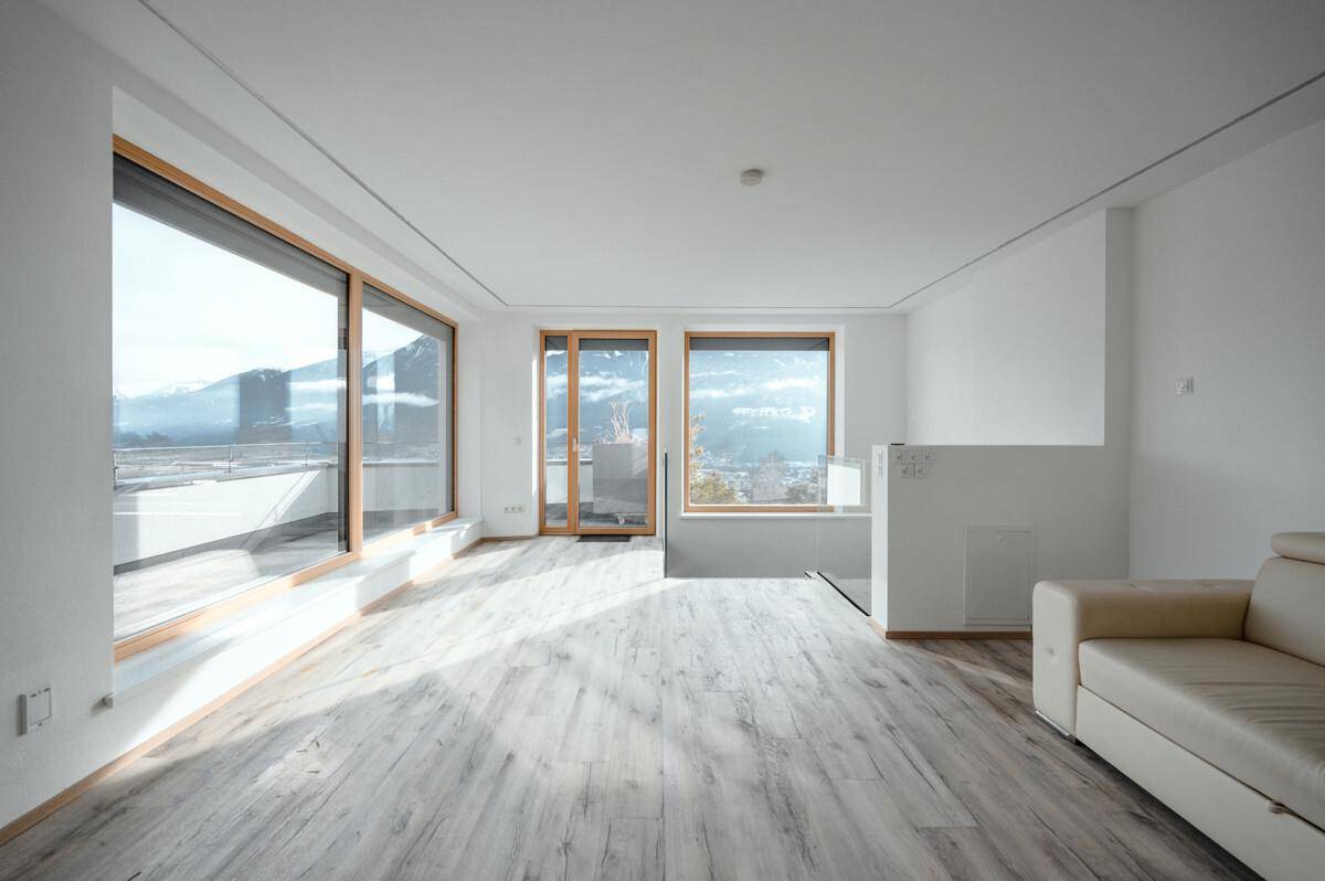 Lichtdurchfluteter Wohnbereich mit großen Fenstern, Bergblick und Zugang zur Terrasse.
