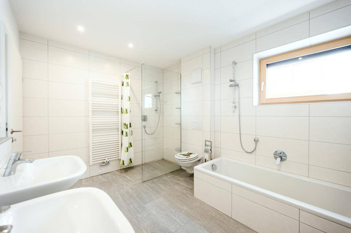 Modernes Badezimmer mit Doppelwaschbecken, Badewanne, Dusche und Fenster.