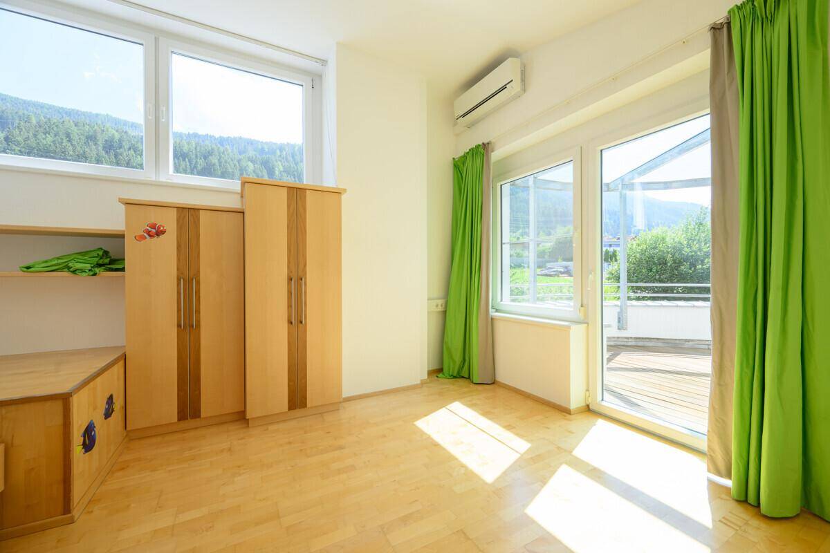 Kinderzimmer mit Kleiderschrank, Klimaanlage und Zugang zu einem Balkon.