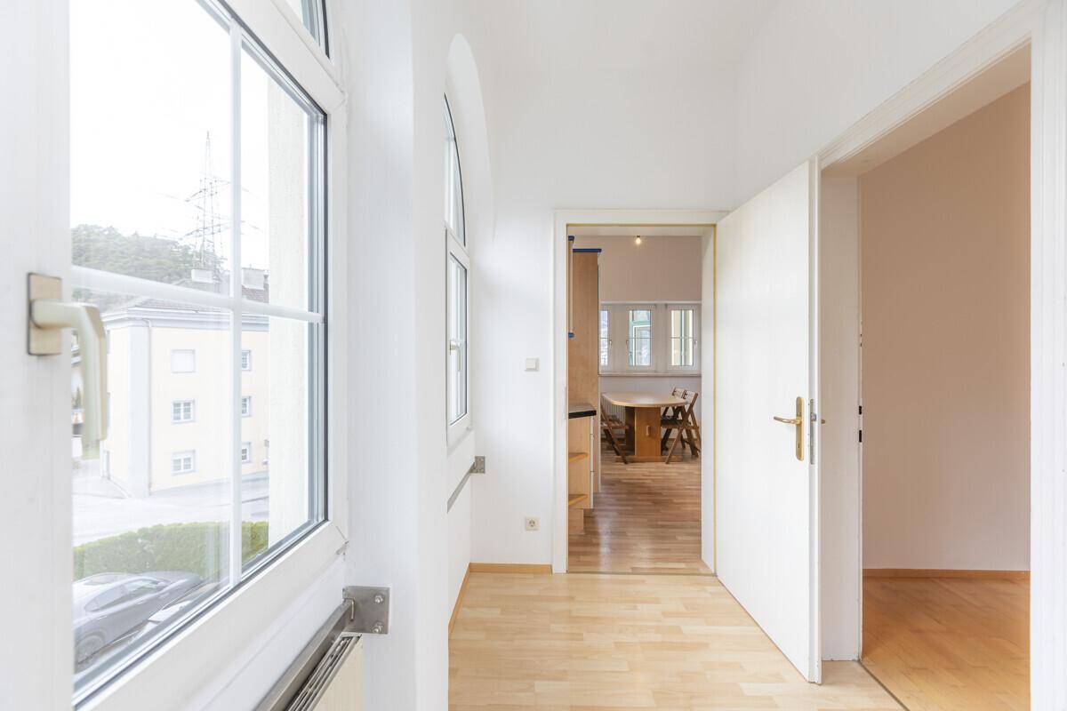 Heller Flur mit Holzboden und Blick in angrenzende Räume durch offene Türen.