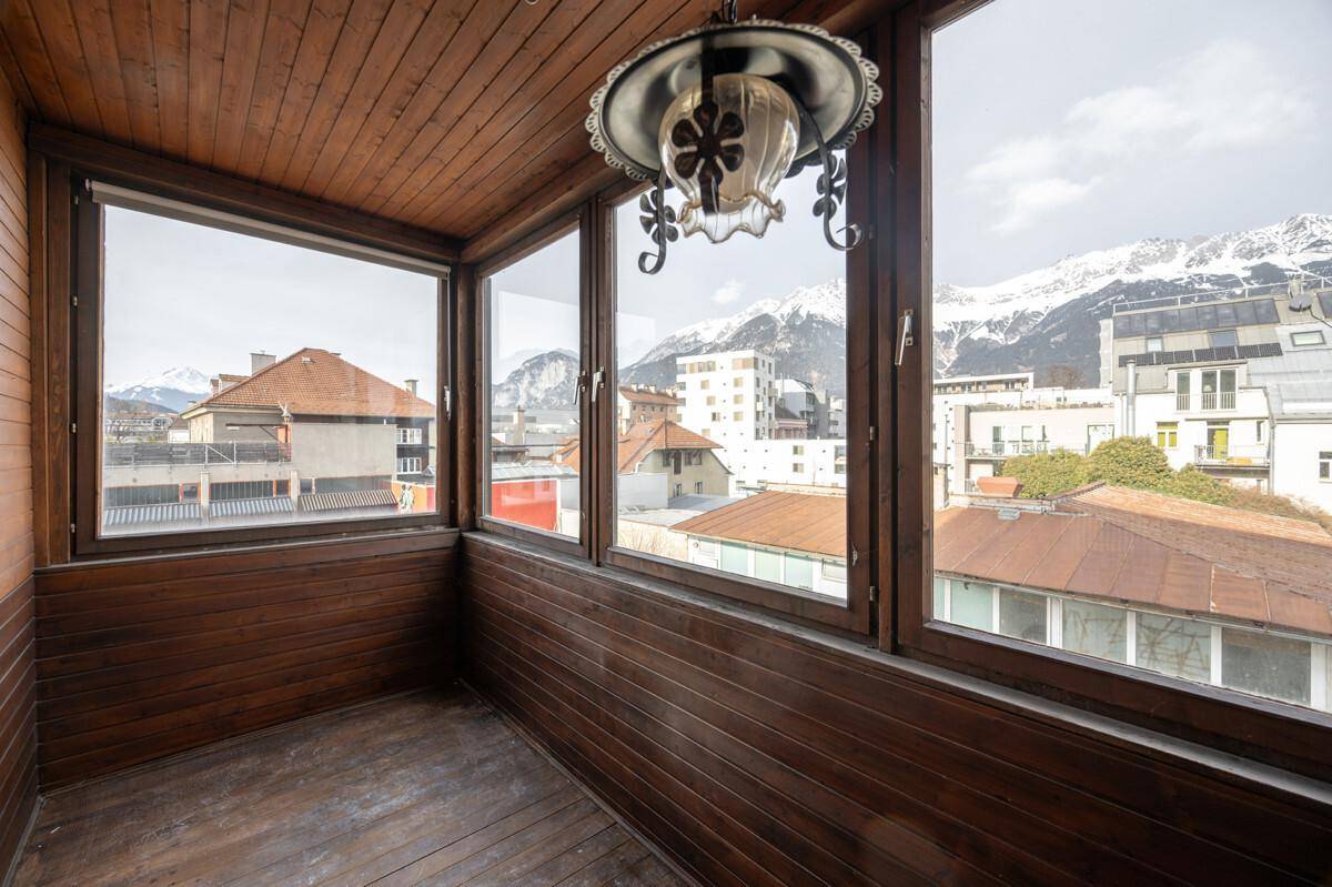 Gemütliche Loggia mit Holzverkleidung, großen Fenstern und beeindruckendem Bergblick.