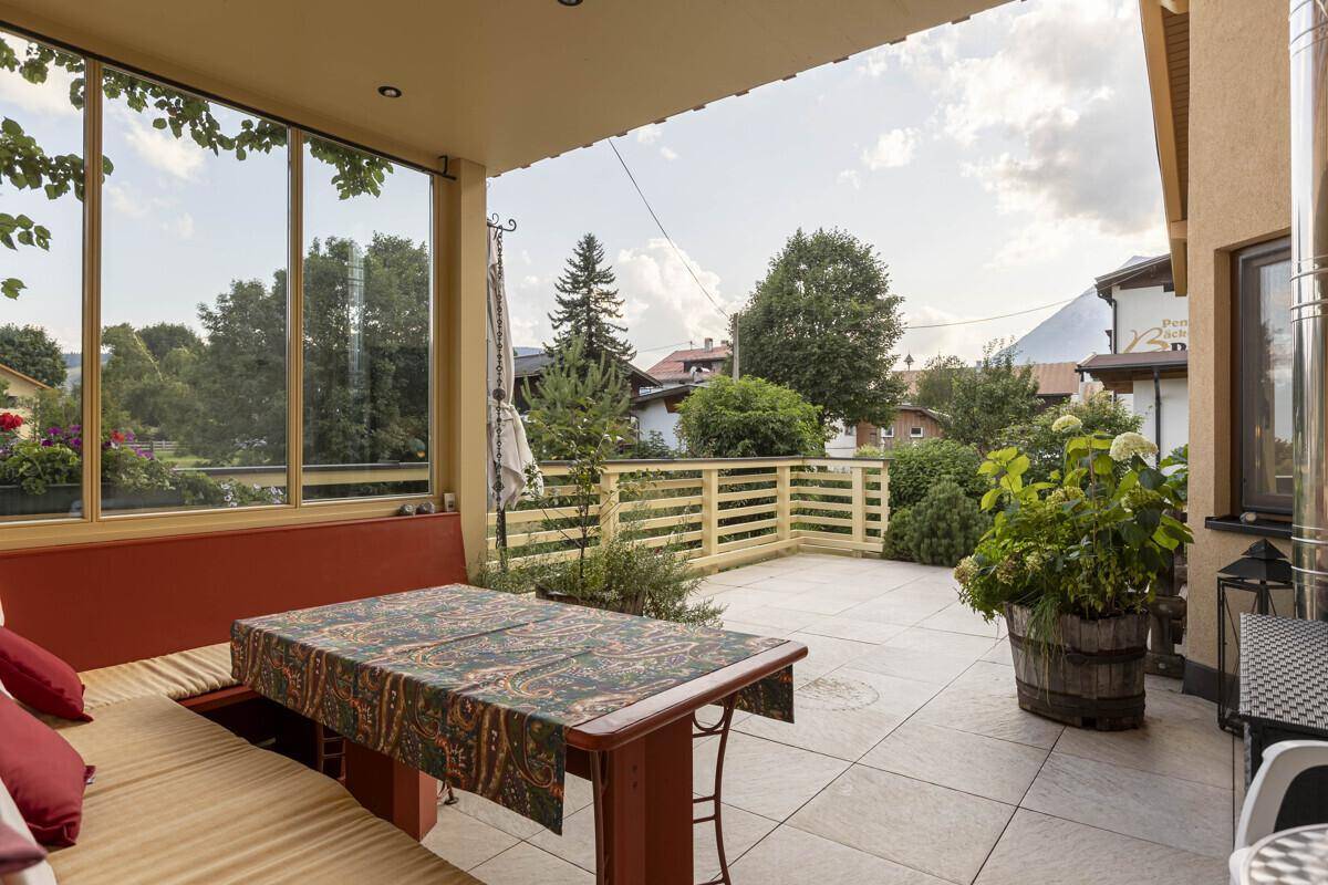 Überdachte Terrasse mit Sitzgelegenheiten und Blick auf die umliegende Landschaft.