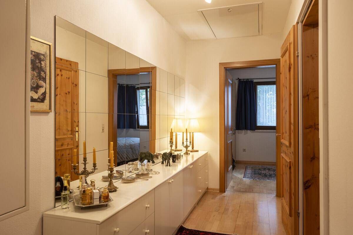 Heller Flur mit Spiegelfronten, Holzboden und Zugang zu weiteren Zimmern.