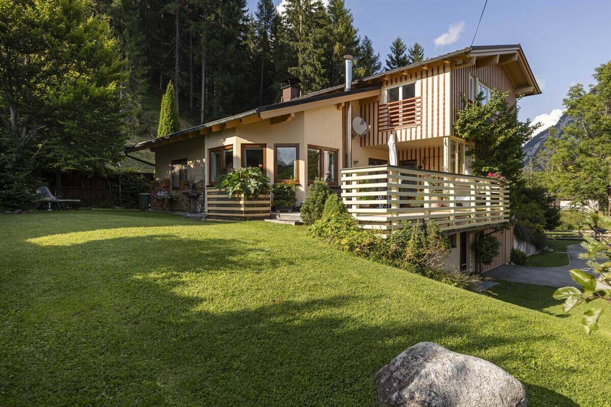Charmantes Haus mit Holzfassade, großem Garten und Terrasse in alpiner Umgebung.