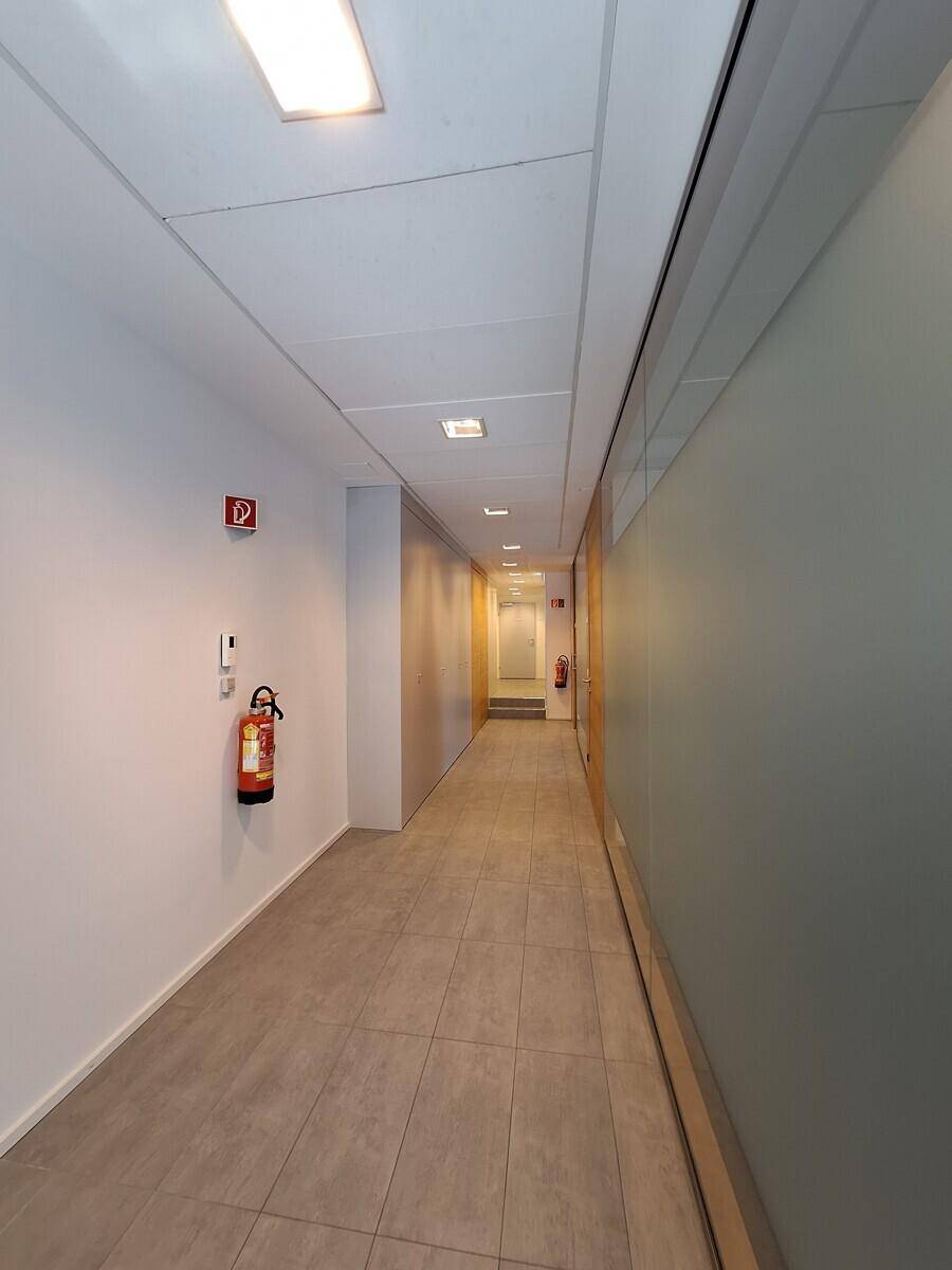 Langer, heller Flur mit Fliesenboden, weißen Wänden und Deckenplatten, ausgestattet mit Brandschutz.
