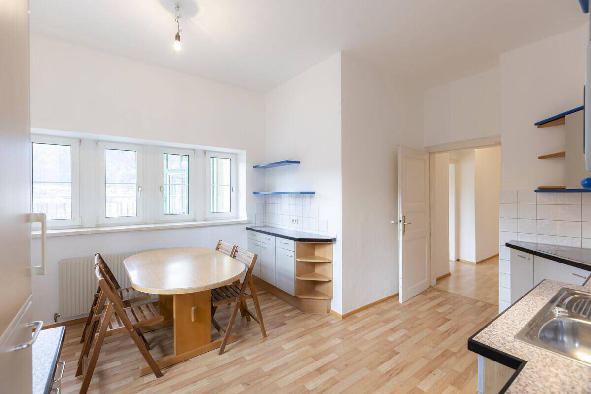 Geräumige Wohnküche mit Esstisch und Blick durch die Fenster ins Freie.