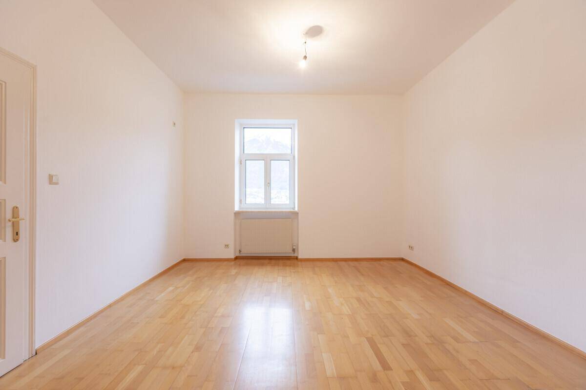 Geräumiges Zimmer mit hellem Holzboden und einem Fenster, das viel Tageslicht hereinlässt.