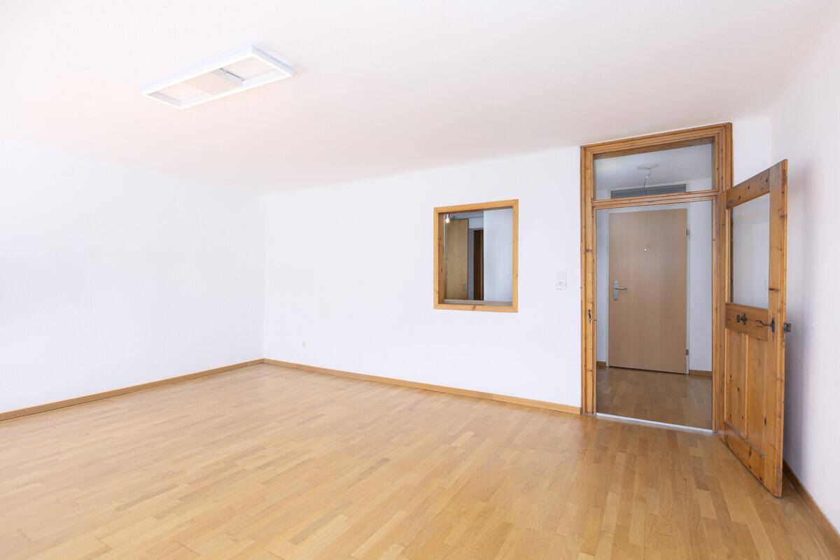 Geräumiger, heller Raum mit Holzboden und Holztür, bereit zur individuellen Gestaltung.