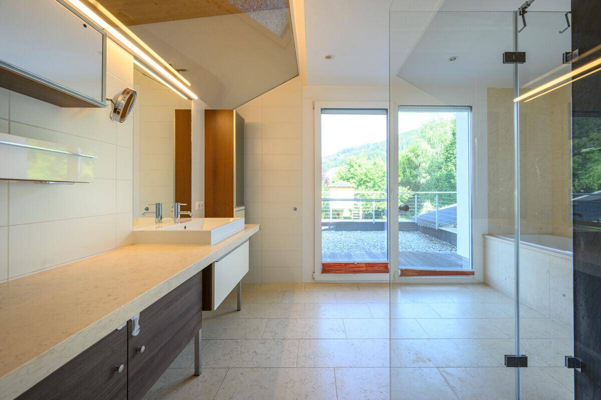 Helles Badezimmer mit modernem Waschbecken, Dusche und Zugang zur Terrasse.