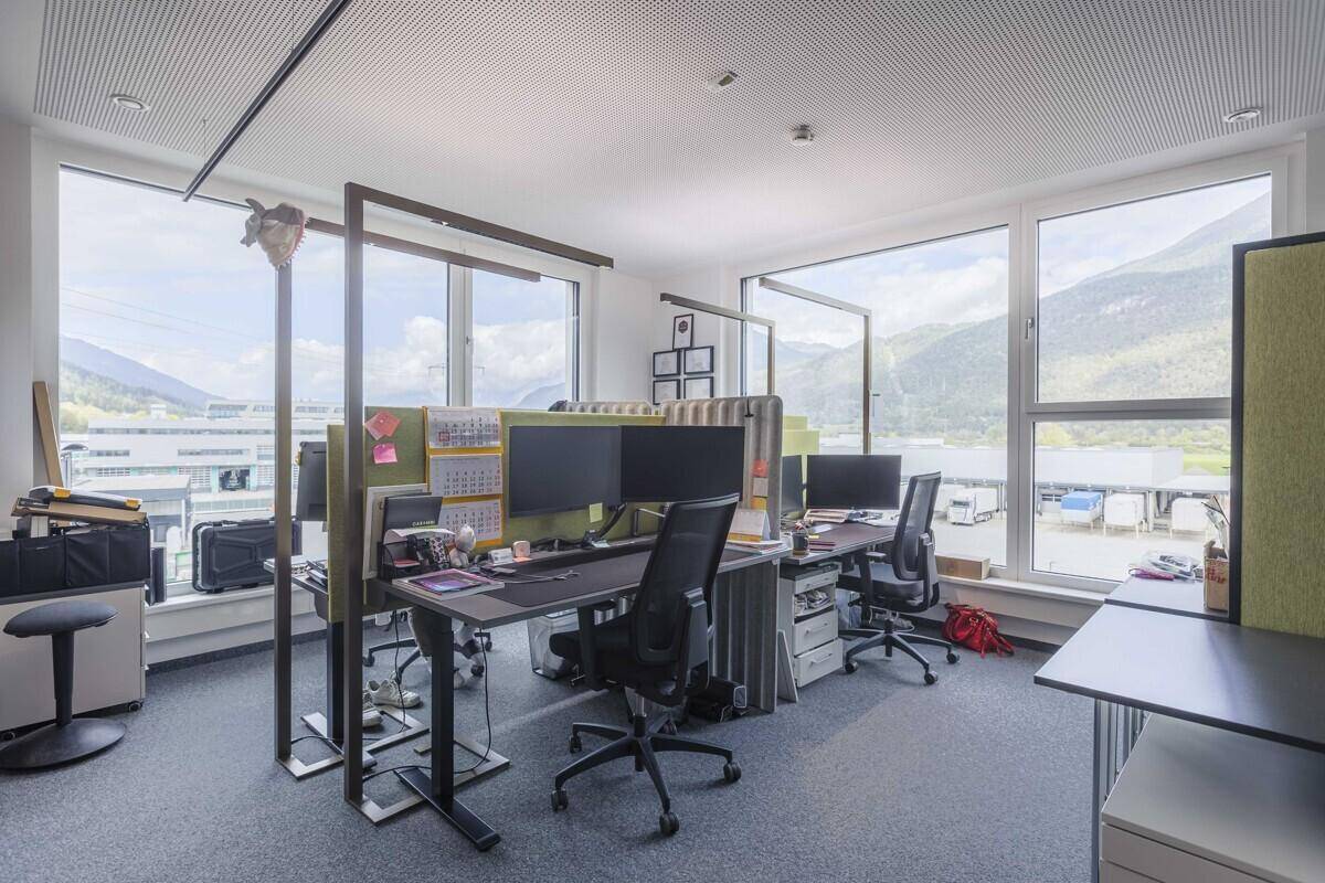 Offener Bürobereich mit mehreren Arbeitsplätzen, Trennwänden und weitem Blick auf die Umgebung.