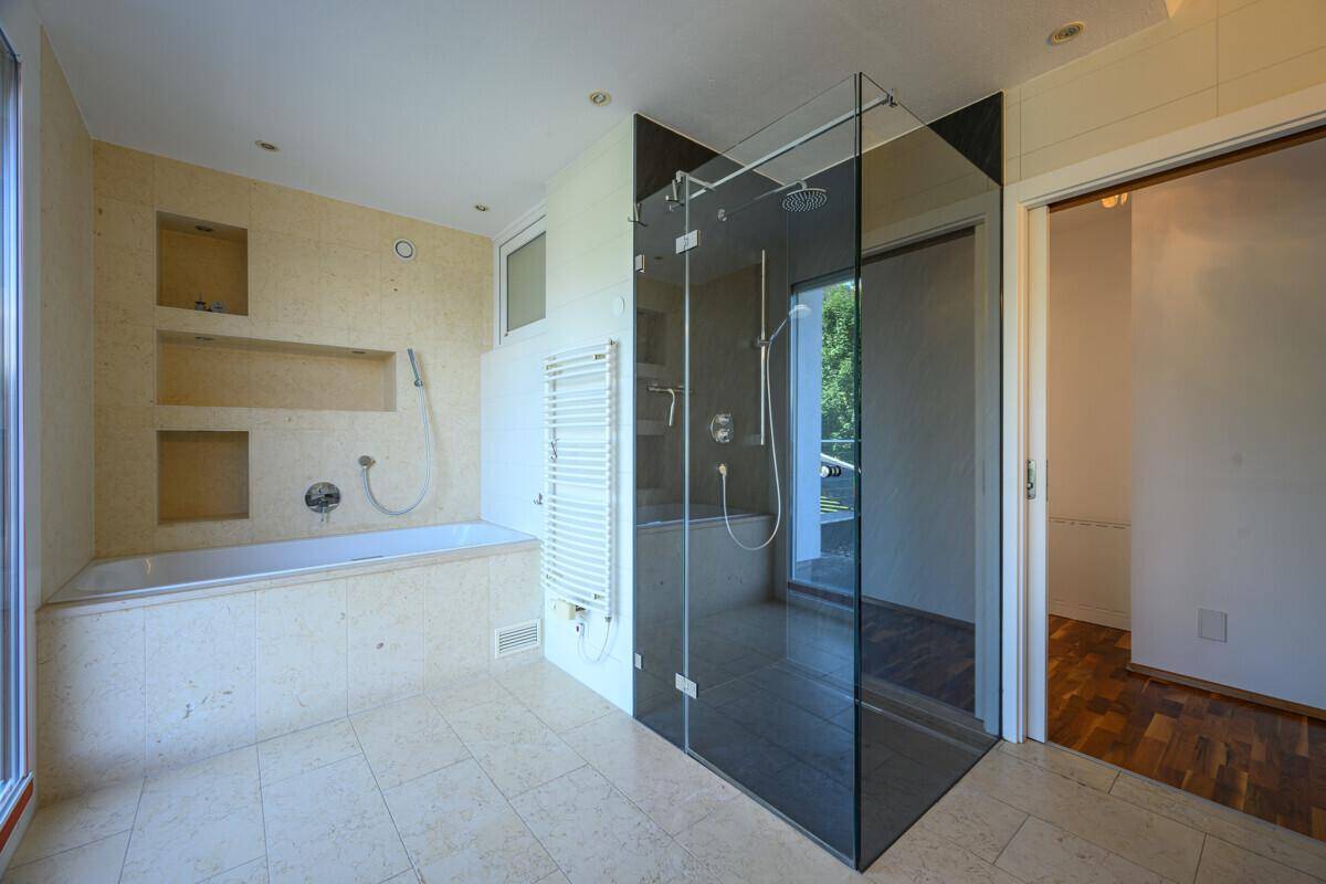 Geräumiges Badezimmer mit Badewanne, begehbarer Dusche und hellen Fliesen.