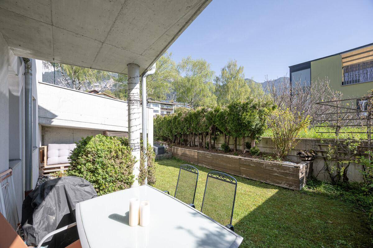 Kleiner, sonniger Gartenbereich mit Sitzgelegenheiten und grüner Bepflanzung.