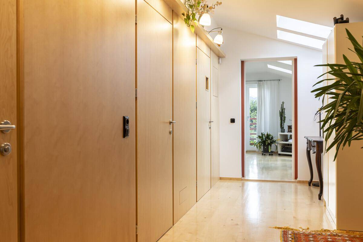 Heller Flur mit Einbauschränken, Holzboden und Dachfenstern für natürliches Licht.