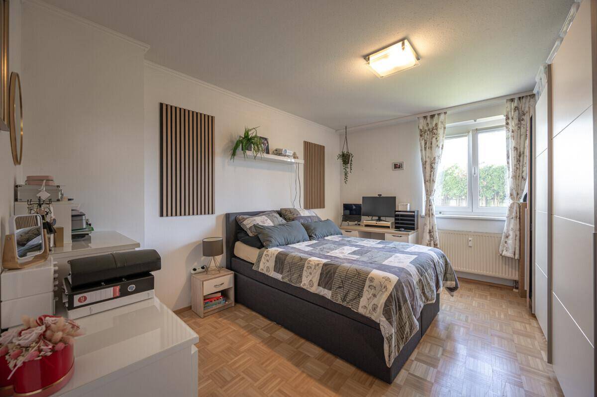 Gemütliches Schlafzimmer mit Parkettboden, großem Bett und Fenster.
