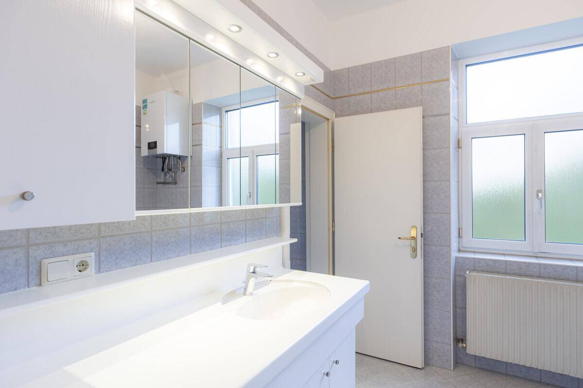 Badezimmer mit Einzelwaschbecken, Spiegelschrank und Fenster für natürliche Belüftung.