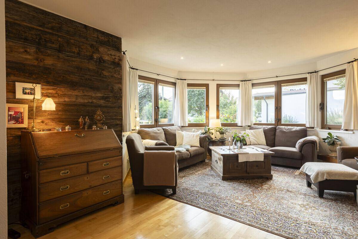 Geräumiges Wohnzimmer mit Holzboden, gemütlichen Sofas und vielen Fenstern für natürliches Licht.