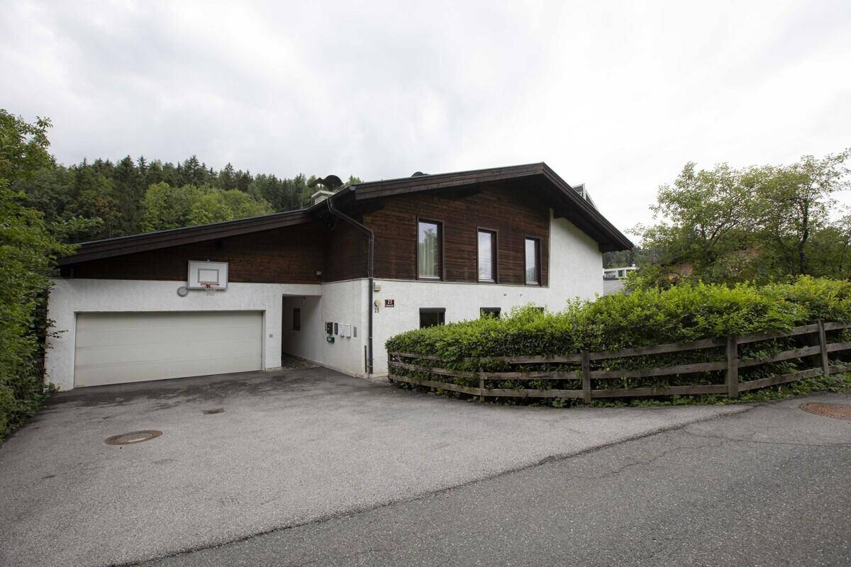 Einfamilienhaus mit Garage, Basketballkorb und gepflegter Hecke an der Zufahrt.