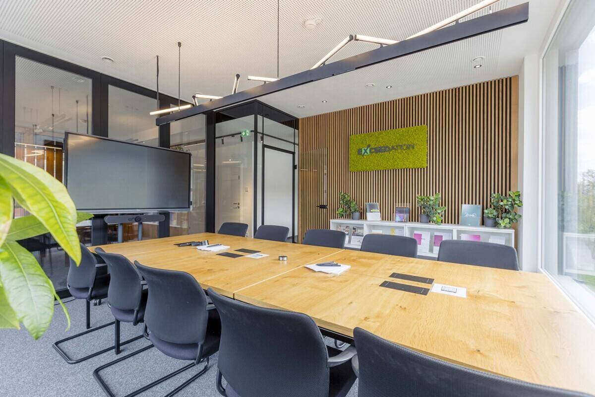 Moderner Konferenzraum mit großem Bildschirm, Holzlamellenwand und stilvoller Einrichtung.