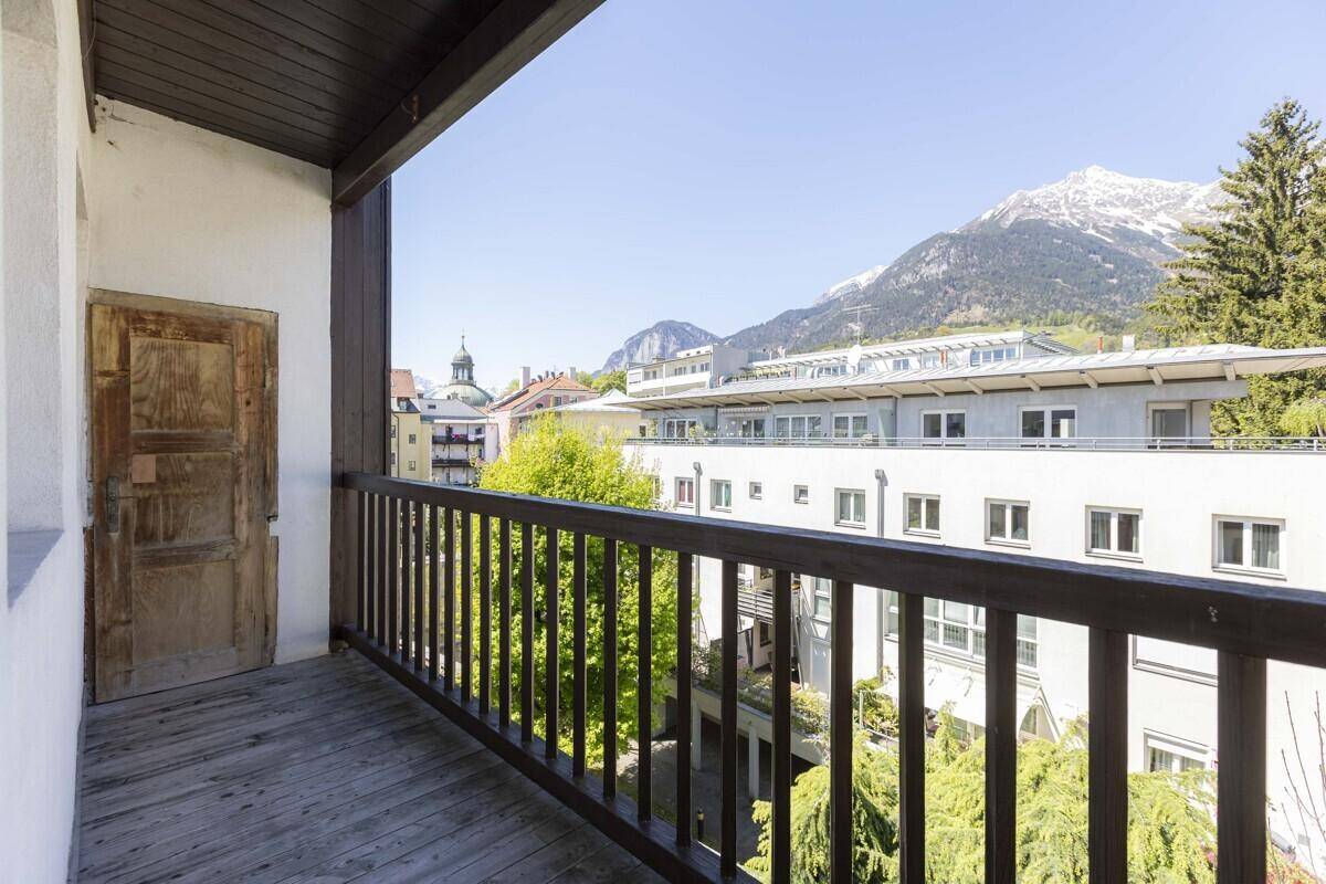 Balkon mit Holzgeländer und weitem Blick auf die Stadt und die umliegenden Berge.