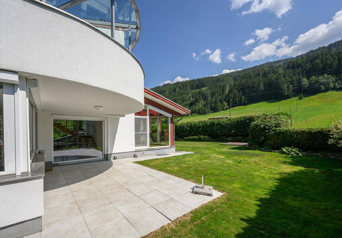 Sonniger Terrassenbereich mit Fliesenboden und direktem Zugang zum grünen Garten.