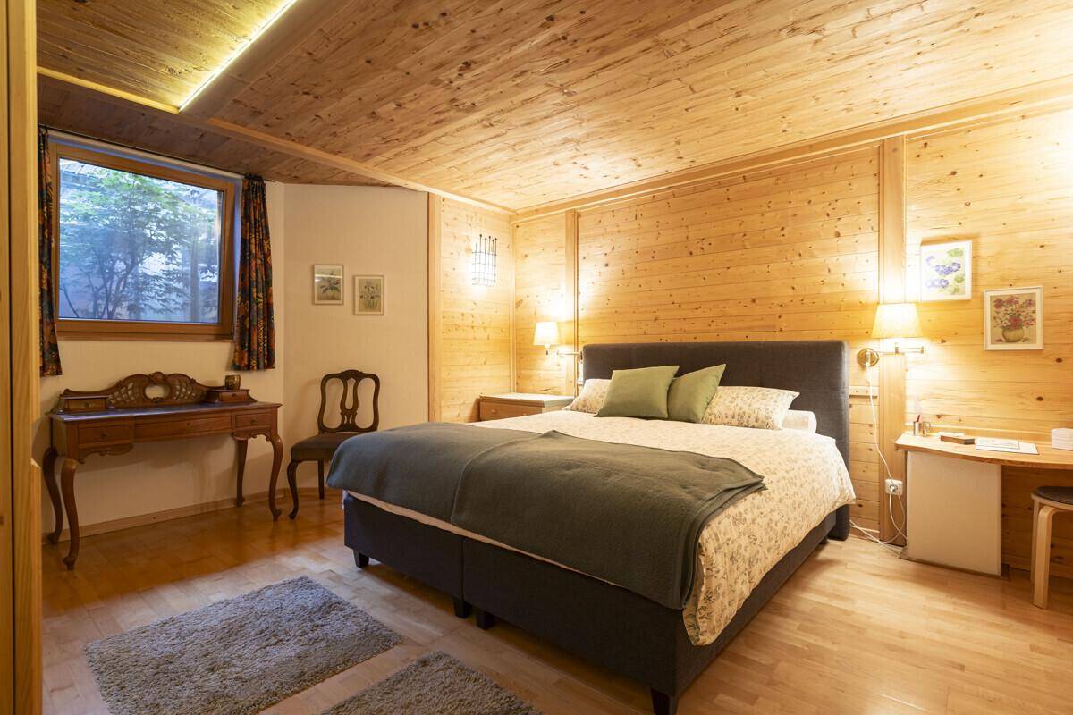 Rustikales Schlafzimmer mit Holzvertäfelung, Doppelbett und Holzboden.