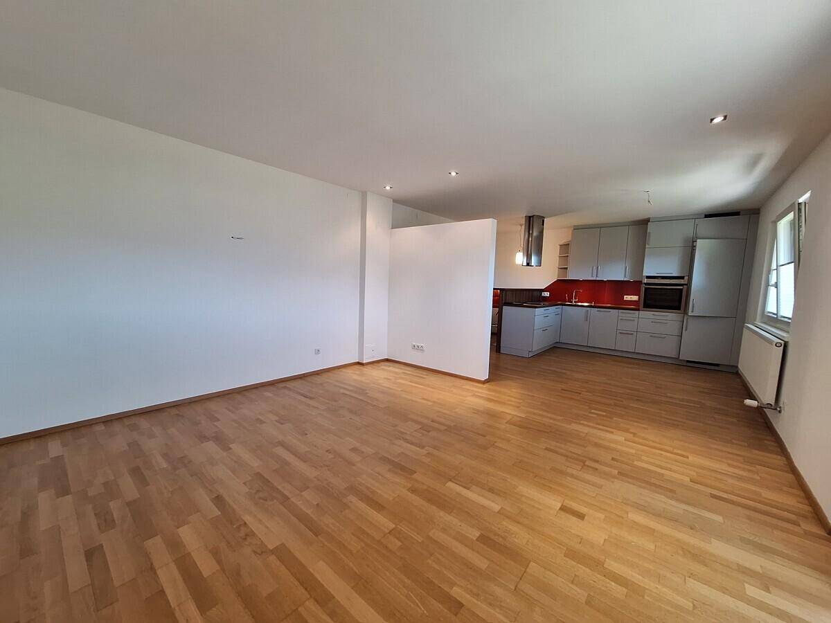 Geräumiger offener Wohnbereich mit integrierter Küche und Parkettboden.