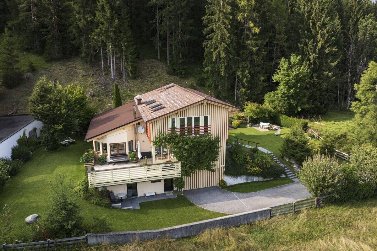 Luftaufnahme des Hauses mit Garten, Terrasse und Zufahrt in einer grünen Landschaft.