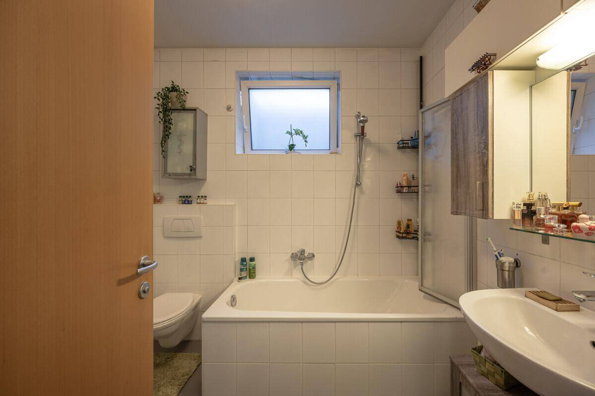 Helles Badezimmer mit Badewanne, WC, Waschbecken und Fenster.