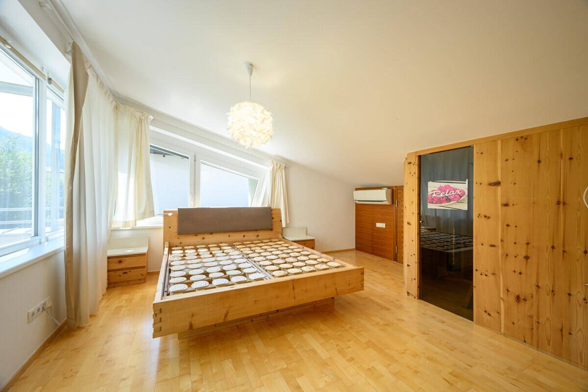 Schlafzimmer mit Holzbett, Parkettboden, Klimaanlage und integrierter Sauna.