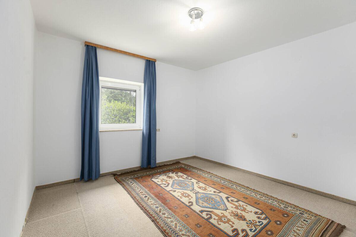 Helles Zimmer mit Teppichboden und blauen Vorhängen, bietet eine ruhige Atmosphäre.