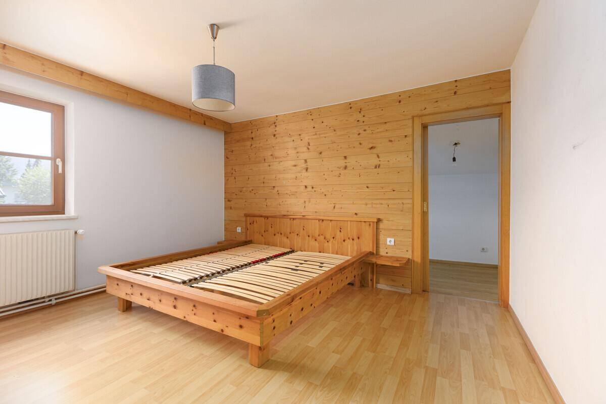 Schlafzimmer mit Holzwand, Holzbettrahmen und Laminatboden, bietet eine gemütliche Atmosphäre.