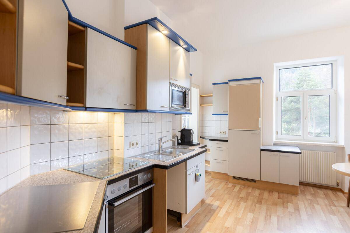 Funktionale Küche mit weißen Schränken, blauen Akzenten und integrierten Geräten.