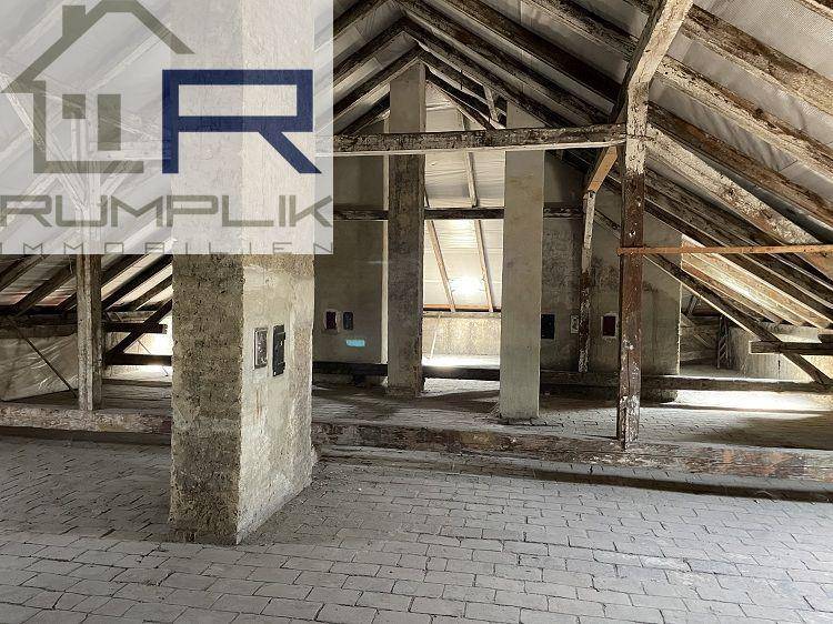 Geräumiger Dachboden mit freiliegenden Holzbalken und Ziegelboden, bereit für den Ausbau.