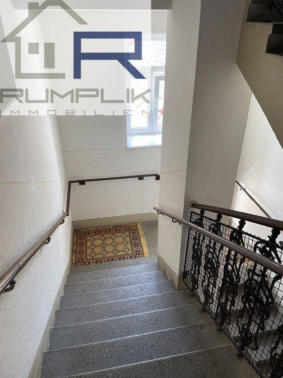 Blick von oben auf das Treppenhaus mit gemustertem Teppich auf dem Treppenabsatz und Fenster.