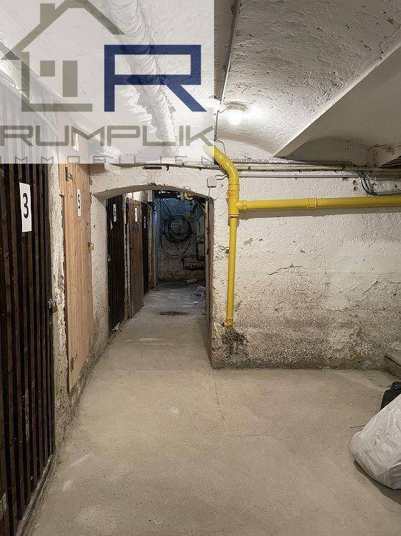 Kellerflur mit individuellen Lagerabteilen und sichtbaren Versorgungsleitungen an der Decke.