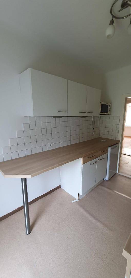 Küchenzeile mit langer Holz-Arbeitsplatte, weißen Oberschränken und Mikrowelle.