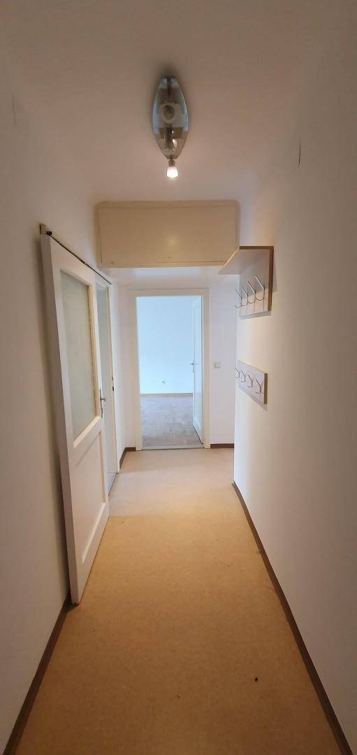 Langer Flur mit Teppichboden und Garderobe, der zu weiteren Räumen führt.