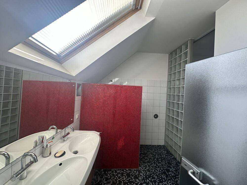Modernes Badezimmer mit Doppelwaschbecken, roten Mosaikfliesen und Dachfenster für viel Licht.