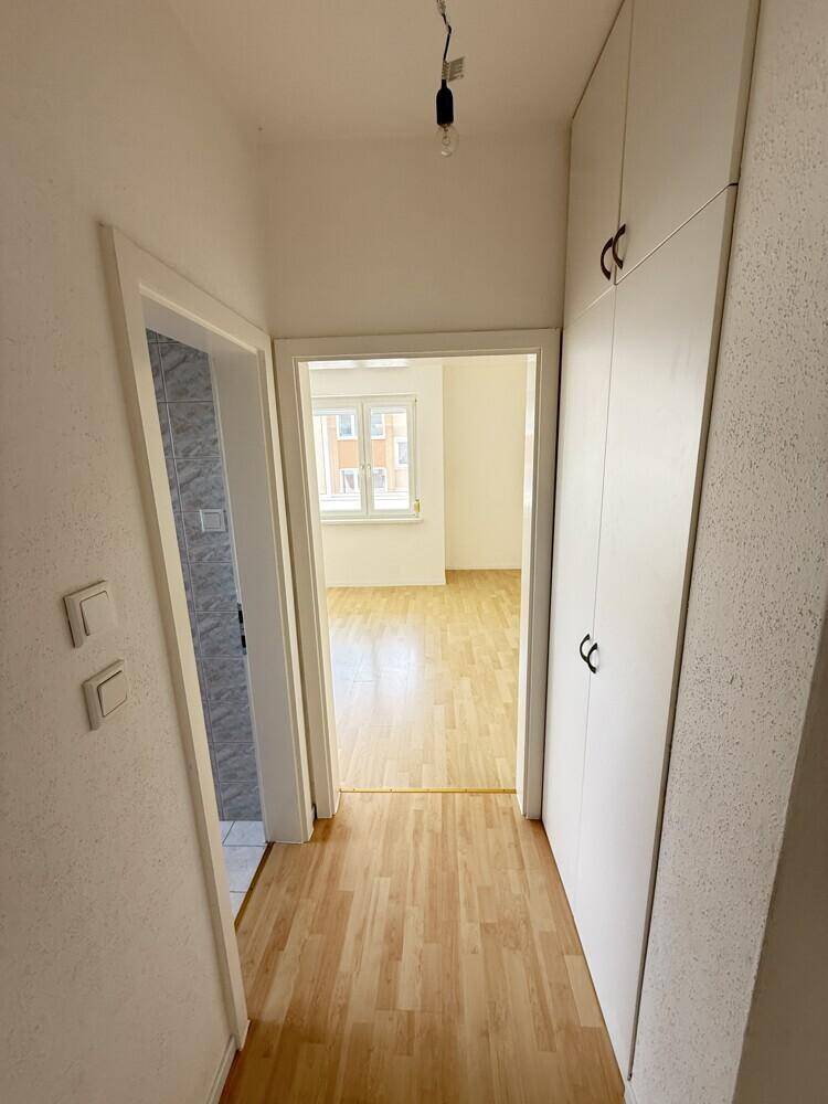 Heller Flur mit Laminatboden, weißen Wänden und praktischen Einbauschränken für Stauraum.
