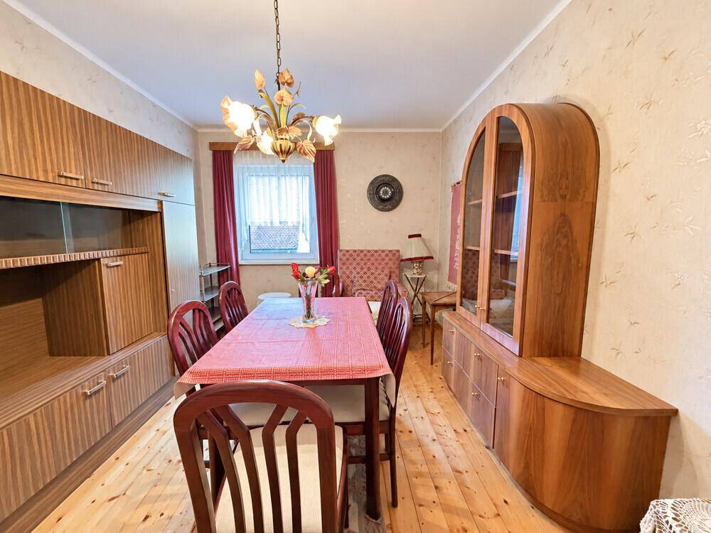 Gemütlicher Essbereich mit Holztisch, passenden Stühlen und einem großen Sideboard mit Vitrine.