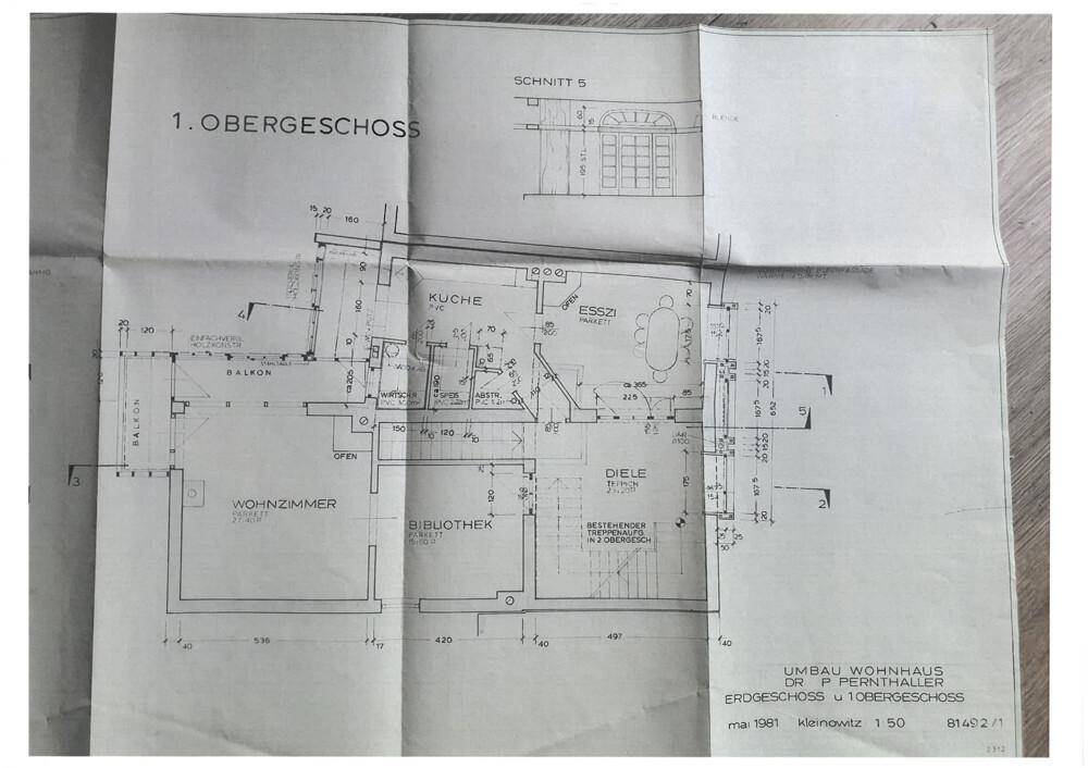 Grundriss des ersten Obergeschosses mit Wohnzimmer, Küche, Essbereich und Balkon.
