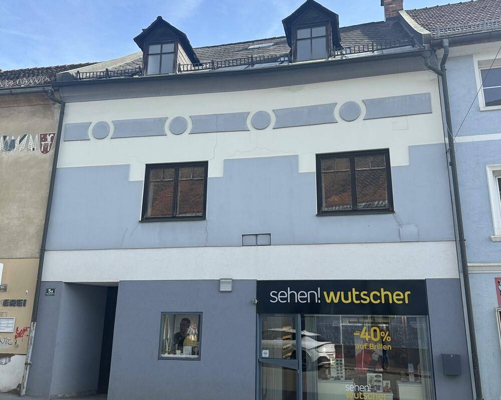 Historische Fassade eines Gebäudes mit Geschäftsfläche im Erdgeschoss und Wohnungen darüber.