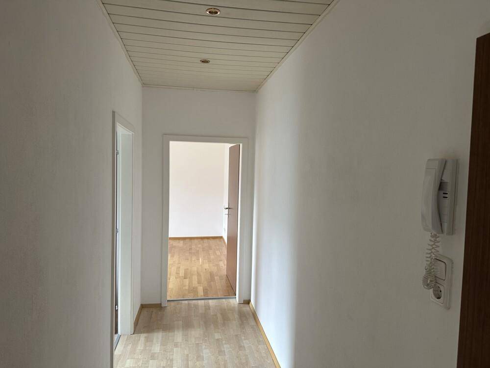 Heller Flur mit Laminatboden und Holzdecke, der zu weiteren Räumen führt.