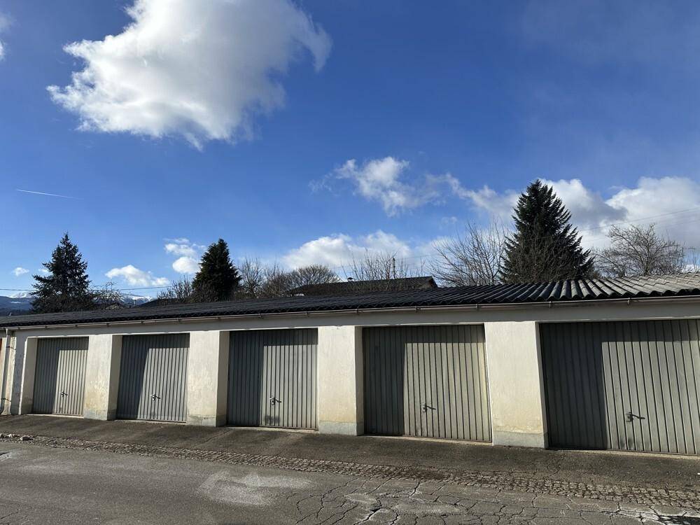 Reihe von Garagen mit grauen Toren unter einem blauen Himmel.
